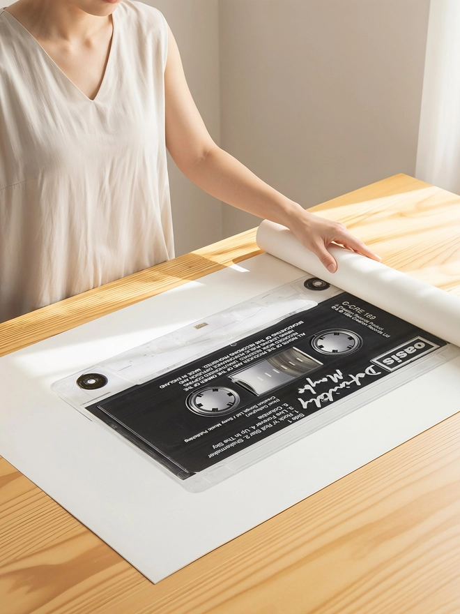 oasis definitely maybe cassette tape print. print being unrolled on wooden tablle.