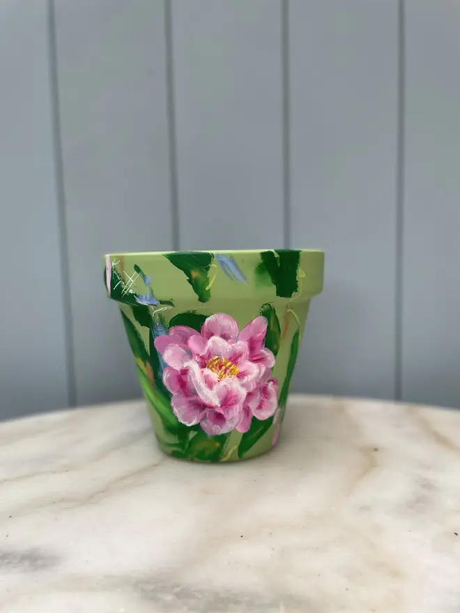 Hand-painted interior terracotta plant pot, featuring a green background adorned with delicate pink peony flowers.