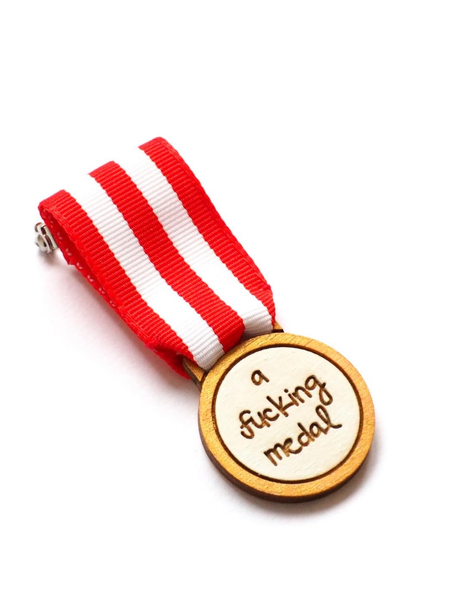 A Wooden Fucking Medal. A wooden medal with red and white ribbon.