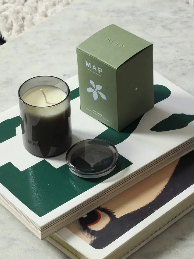 rest aromatherapy candle and home fragrance spray set. candle and spray bottle stacked on top of coffee table books.