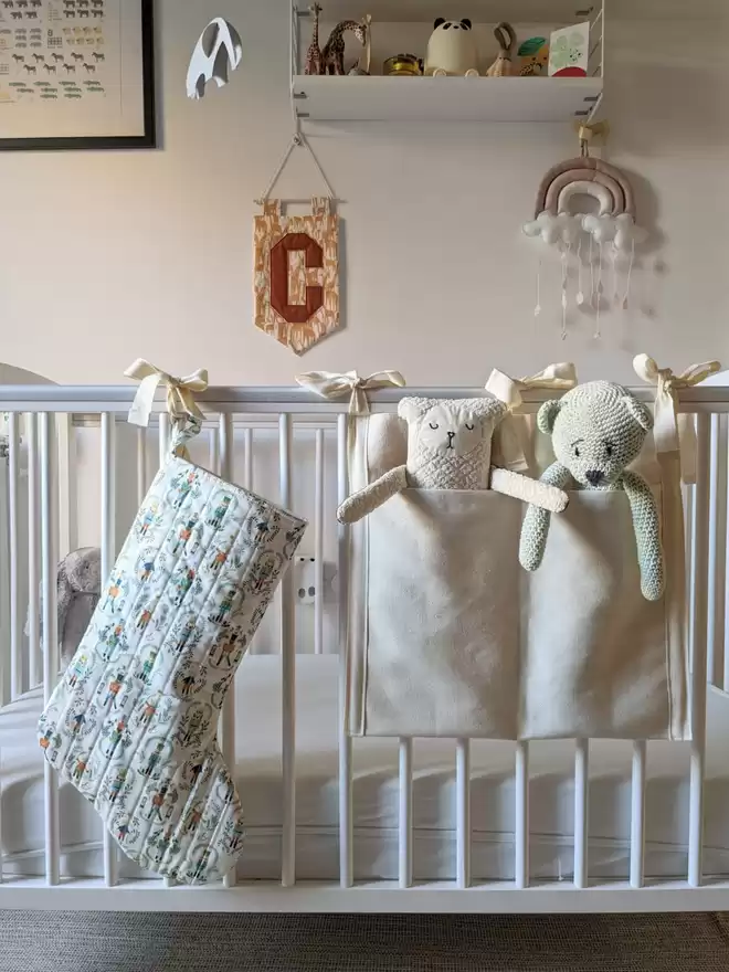 Cooper and Fred nutcracker stocking seen hanging on a cot with two teddy bears.