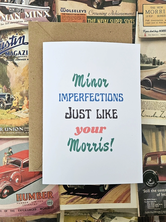 A birthday card that says minor imperfections just like your Morris written in vintage style font on a white card. The colours of the words are green, blue, red and black
