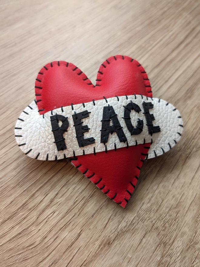 Hetty and Dave red leatherette heart brooch with PEACE in black lettering across a white scroll