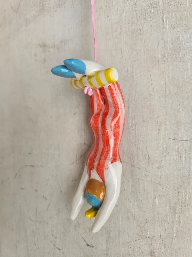 female acrobat hanging upside down in a red and pink stripe suit, back view