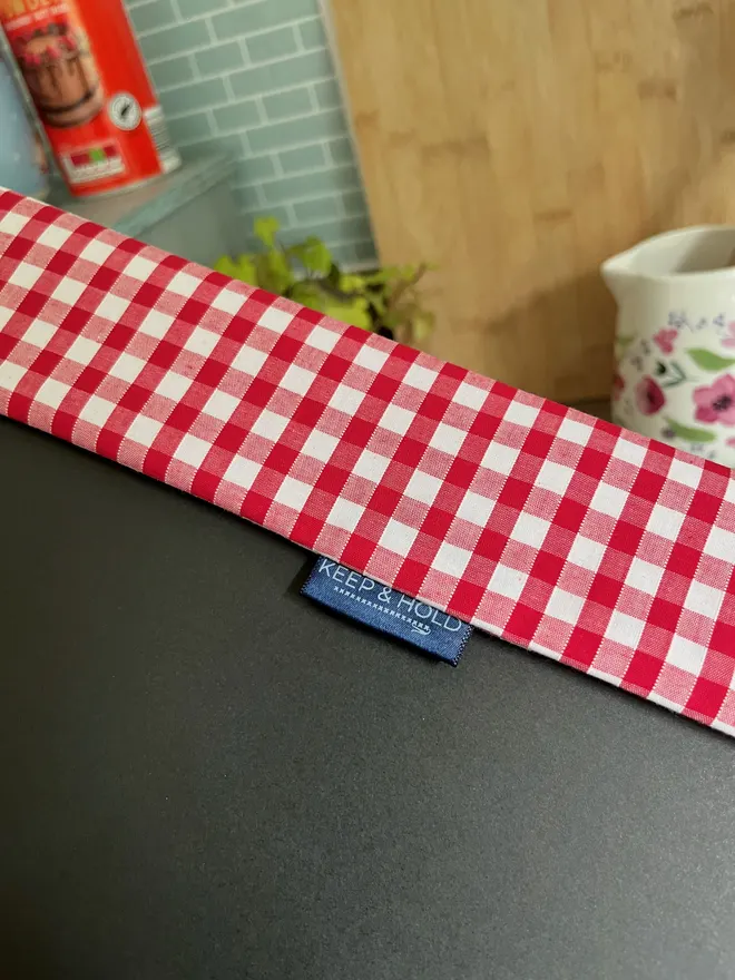 Gingham binder cover inner overlap showing a navy Keep & Hold logo label sewn into seam