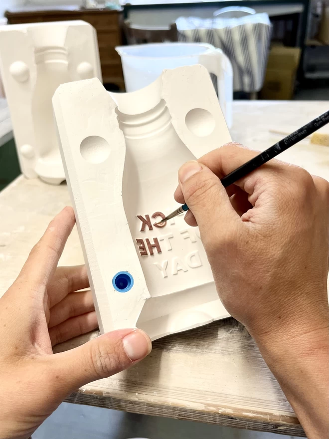 Katie hand paints the words ‘pick of the day’ on the inside of a bottle mould, ready for casting.