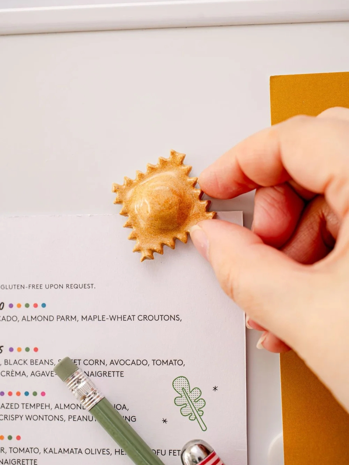 ceramic pasta magnet. a ceramic raviolini magnet on a fridge door.