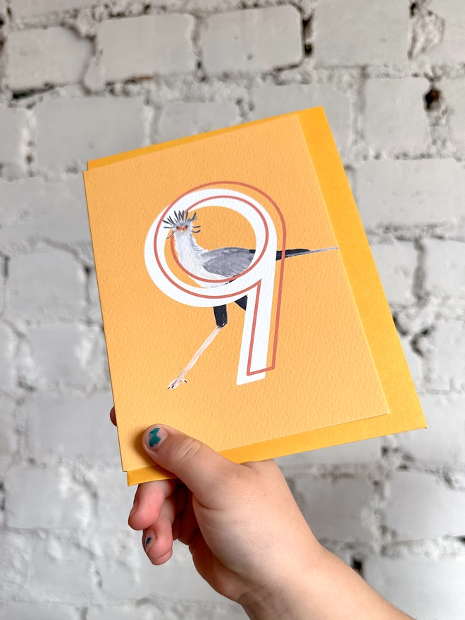 Bright yellow card with an illustration of a secretary bird and a big white number 9, with a yellow envelope