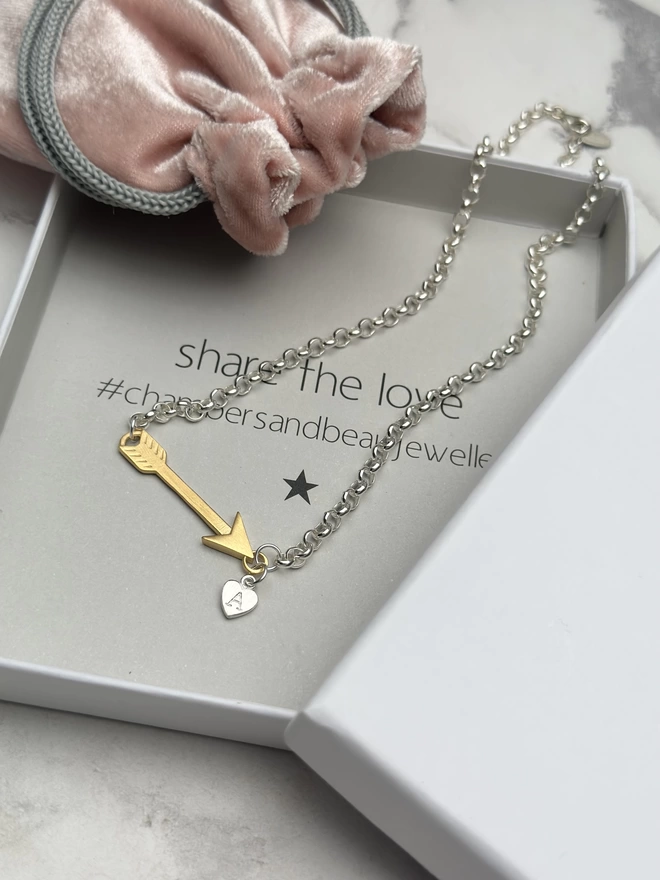 sterling silver chain with gold horizontal feather charm. a small silver heart charm hangs from the chain next to the feather
