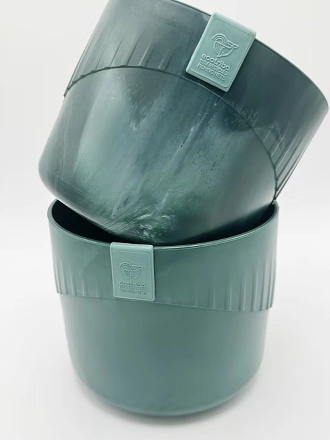 Ocean Plastic Plant Pot Small, a green recycled plant pot sitting on a white surface against a plain backdrop. 