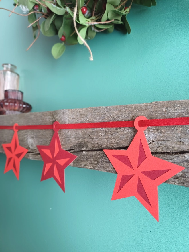 Red Star Garland On Wooden Mantel, Decorations Alternate Between 2 Tones of Red