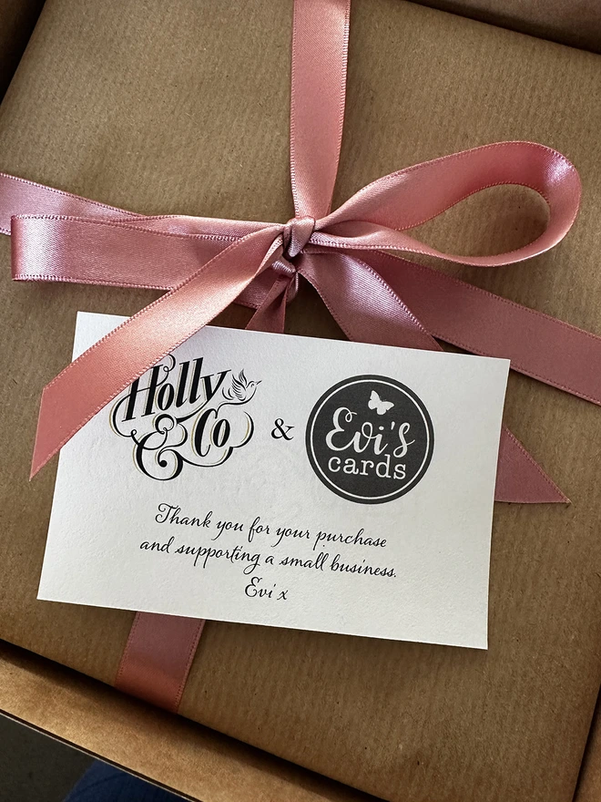 A photo of a gift wrapped framed butterflygram. Select gift wrapped option for free. Wrapped in brown recycled kraft paper, with a hand tied silk pint bow.