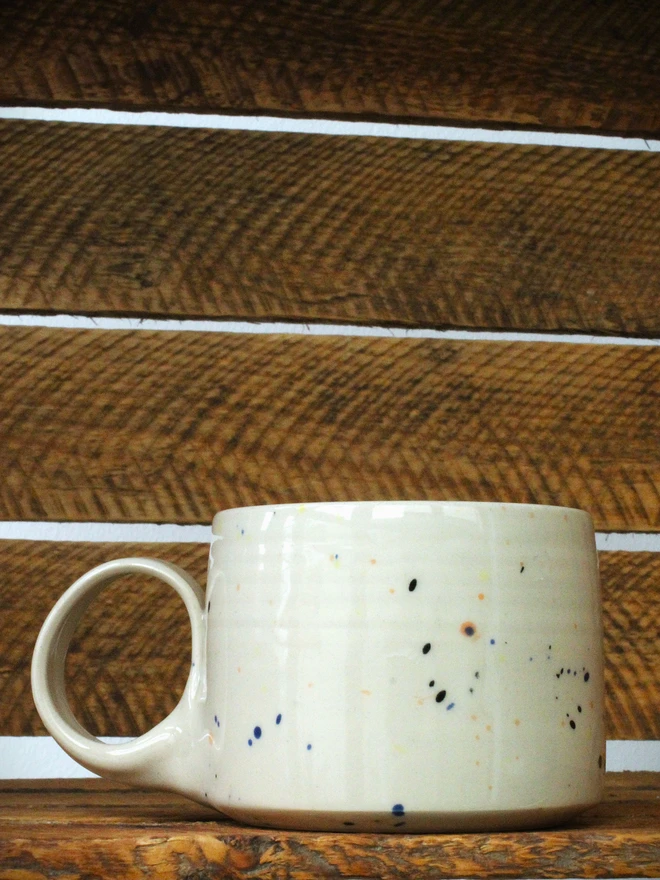 Small creamy white terrazzo cups with black, blue, and yellow splatters and glossy glaze