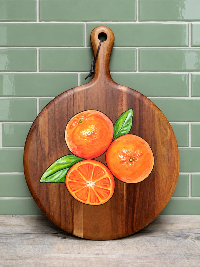 Wooden serving board with a handpainted design of some clementines