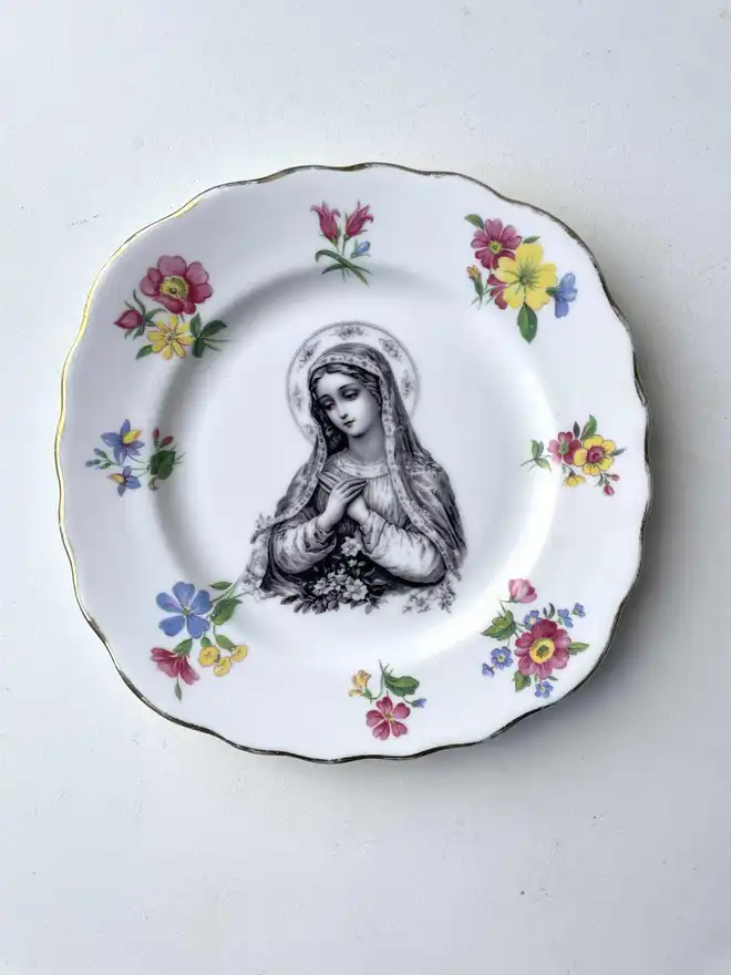 a vintage plate with a really ornate border has the victorian black and white illustration of the virgin mary in the centre