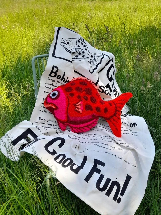 Gorgeous Big Red Fish Cushion on Chair covered in oversized newsprint in a field 