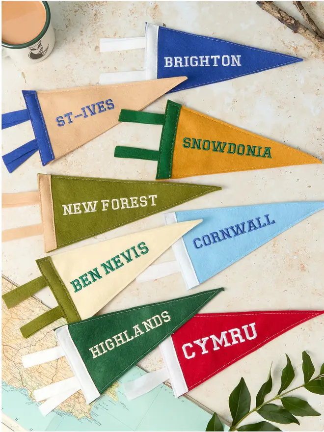 A flat lay of lots of embroidered mini pennant flags displayed in a stone background