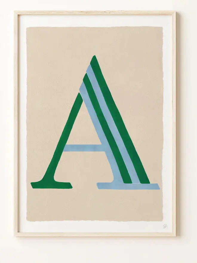 Framed wall art print featuring a large decorative letter “A” in humbug stripes
centered on a white background. 