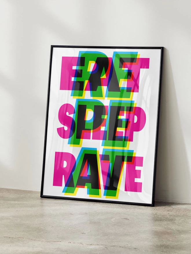 A modern typographic art print featuring the words "Eat Sleep Rave Repeat" in overlapping, vibrant letters of pink, green, blue, and yellow, displayed in a sleek black frame leaning against a white wall.