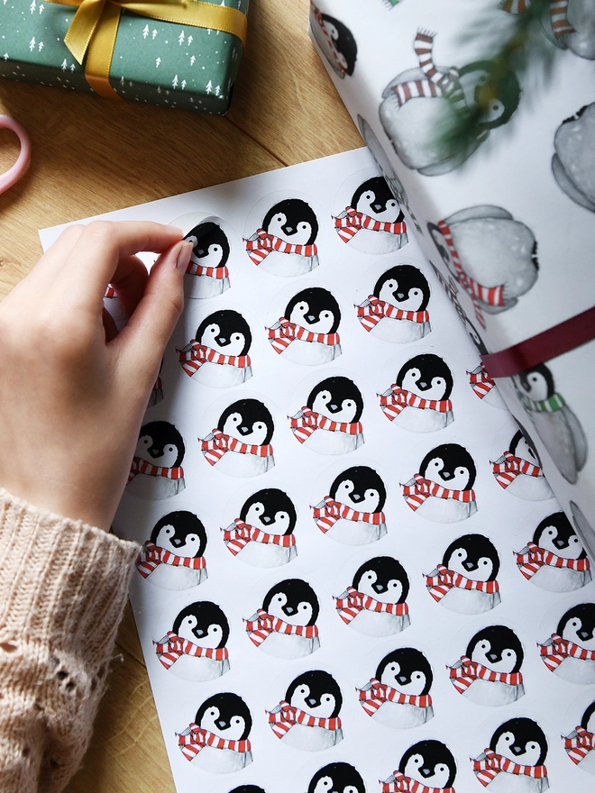 A sticker with a baby penguin design is being peeled from a sheet of 35 stickers.