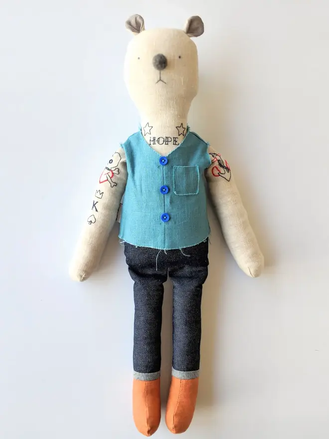 tattooed bear doll. a cream linen bear doll with embroidered arm tattoos and a blue waistcoat.