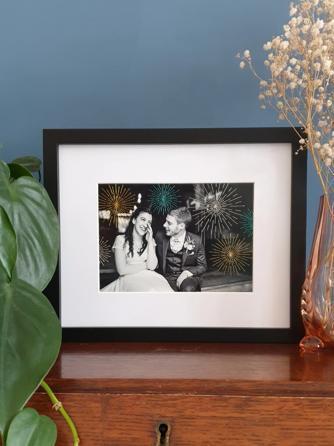 Wedding photo in B&W with hand embroidered sparkly fireworks in black frame on desk
