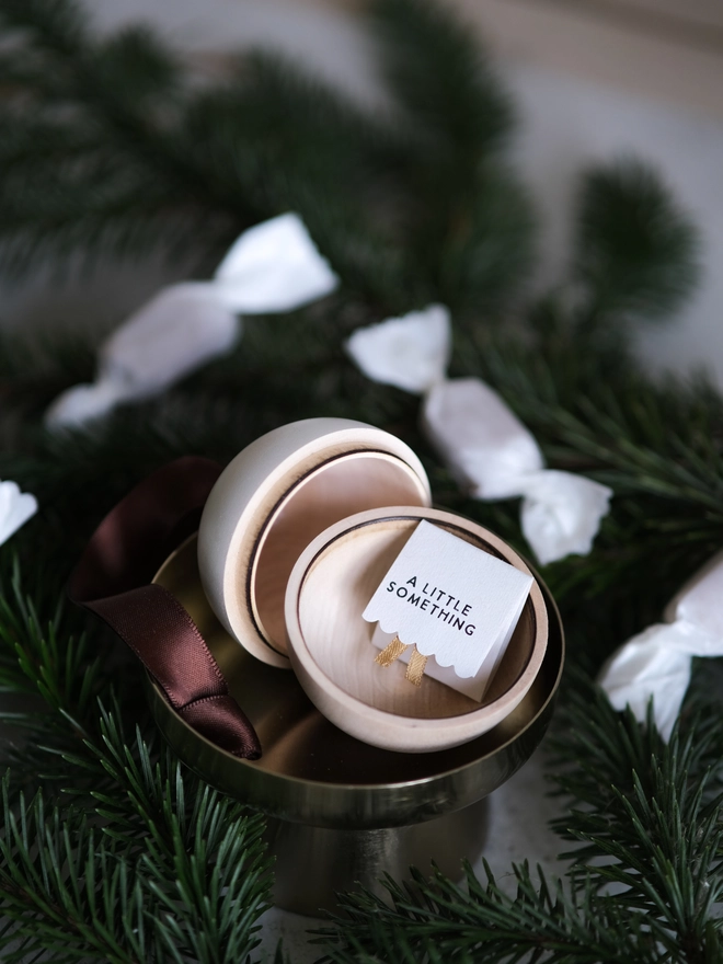 Wooden and white Christmas gift bauble with a removable lid, hanging from a Christmas tree with a space inside for a handwritten message, gift or surprise