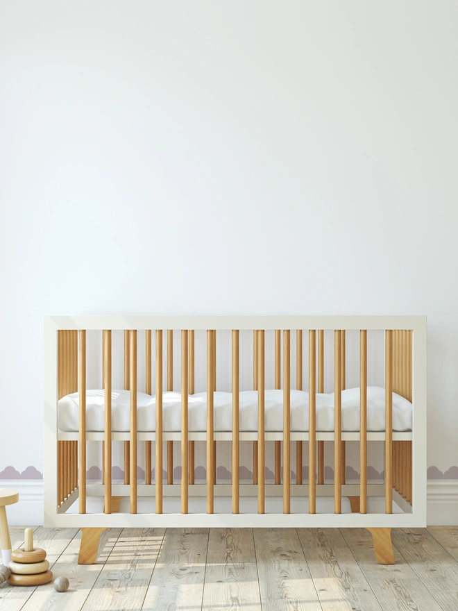 Temple Scallop in Lilac framing a white wall on the skirting board and window frame with a cot in front of the wall