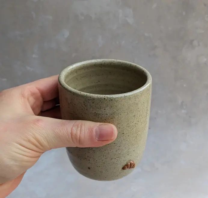 Biscuit coloured croissant coffee cup with a subtle croissant design, placed against a grey marble background.