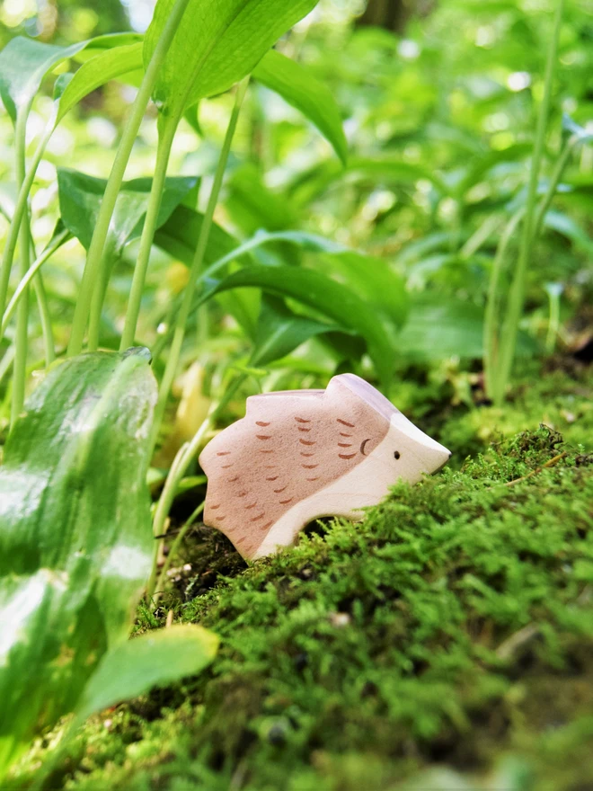 wooden toy hedgehog on a mossy log