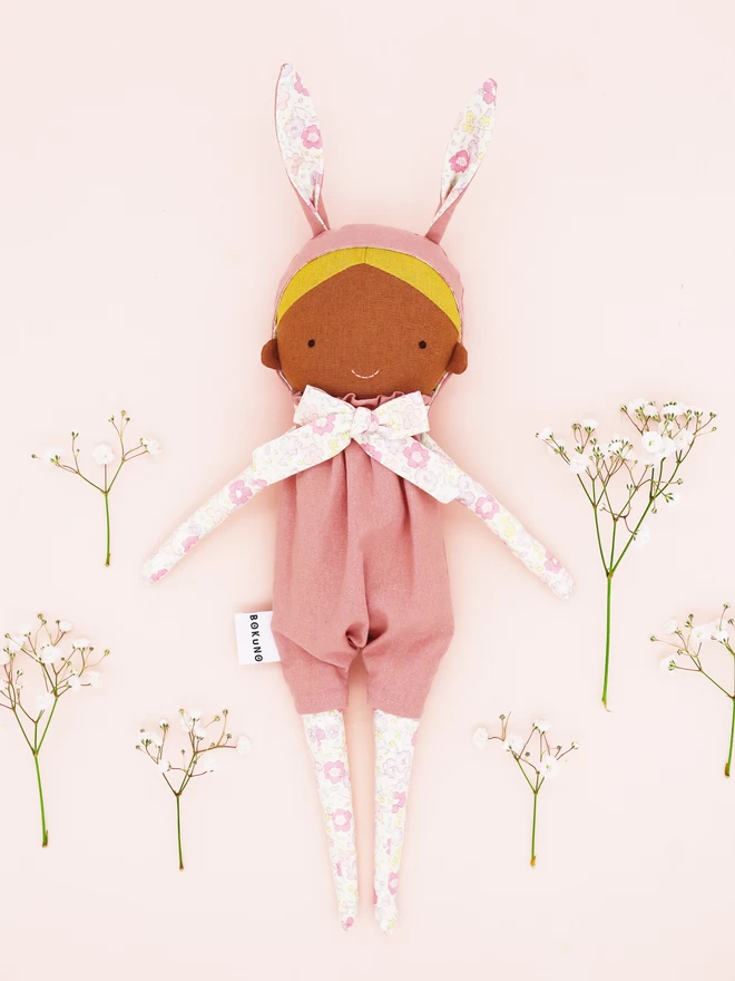 textile girl doll with brown skin and blonde hair wearing pink bunny outfit
