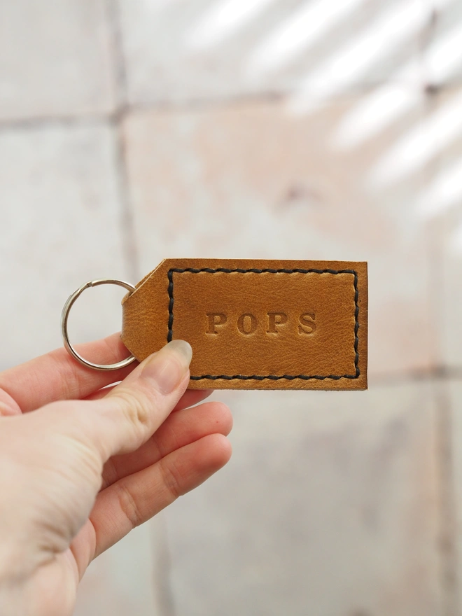 Personalised leather key ring with the name POPS. Hand stitched with black thread