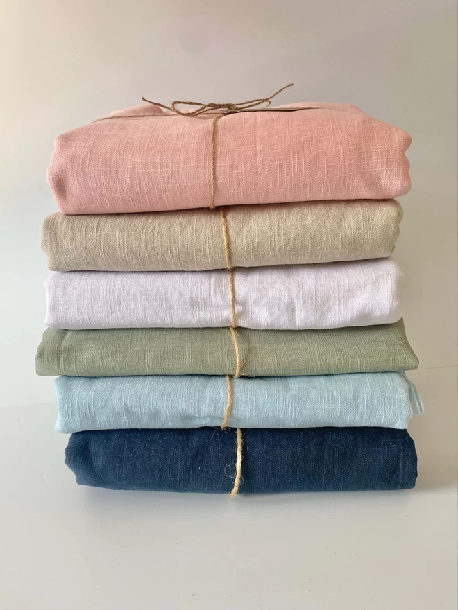 A pile of plain linen tablecloths in an array of colours
