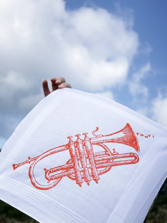 A Mr.PS Toot trumpet hankie held aloft against a blue sky with the wind blowing the fabric