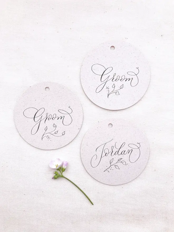circular calligraphy wedding place cards. white circular place card with black calligraphy.