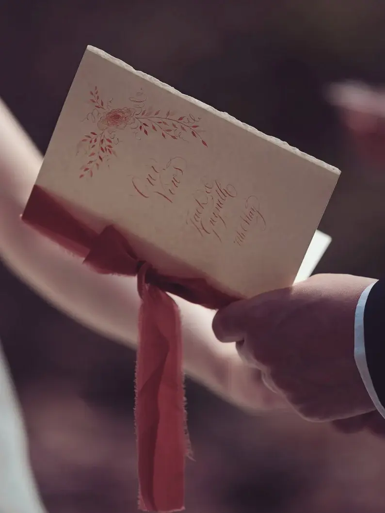 personalised calligraphy wedding vow booklet. white booklet with rust red calligraphy on cover.