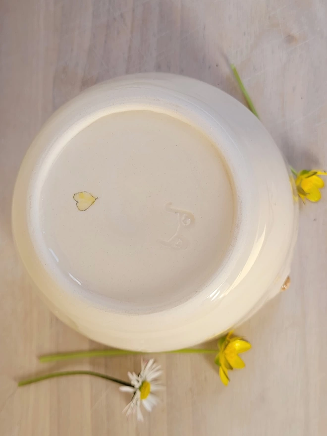 the base of a hand made cup with a hand painted yellow heart