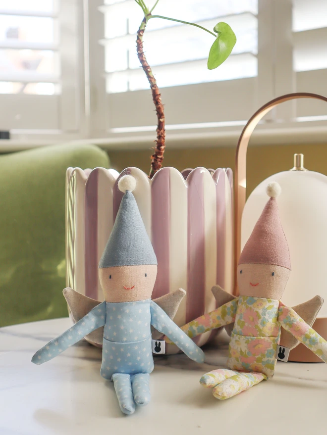 Small fairy dolls in blue and pink linen pointy hat, blue star and pink floral printed outfit and natural linen wings.