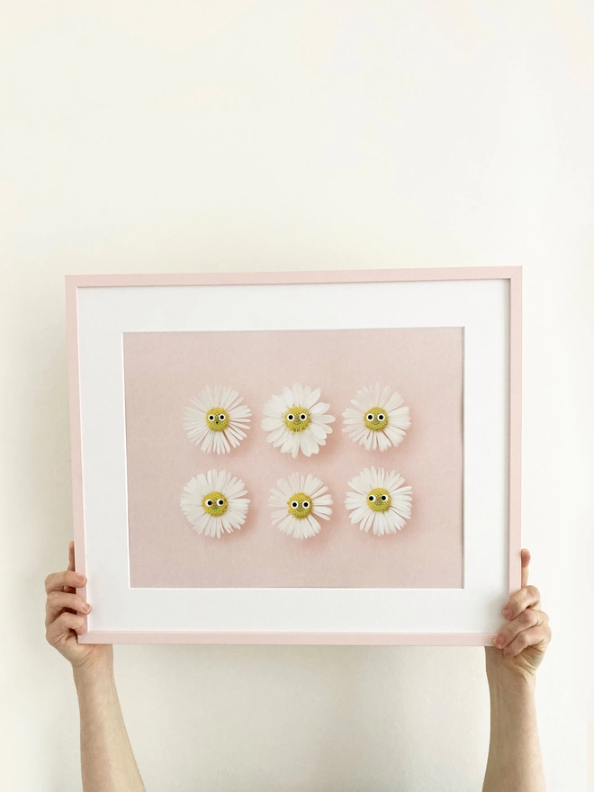 someone holding a framed A3 print of smiling daisies 