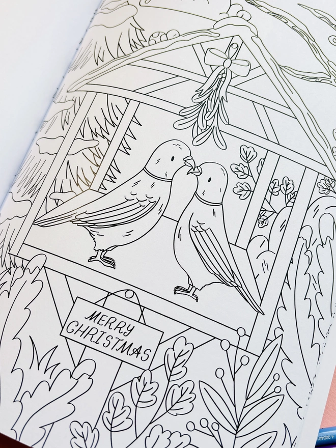 Woodland Christmas colouring book displayed with colouring pencils and winter decorations.