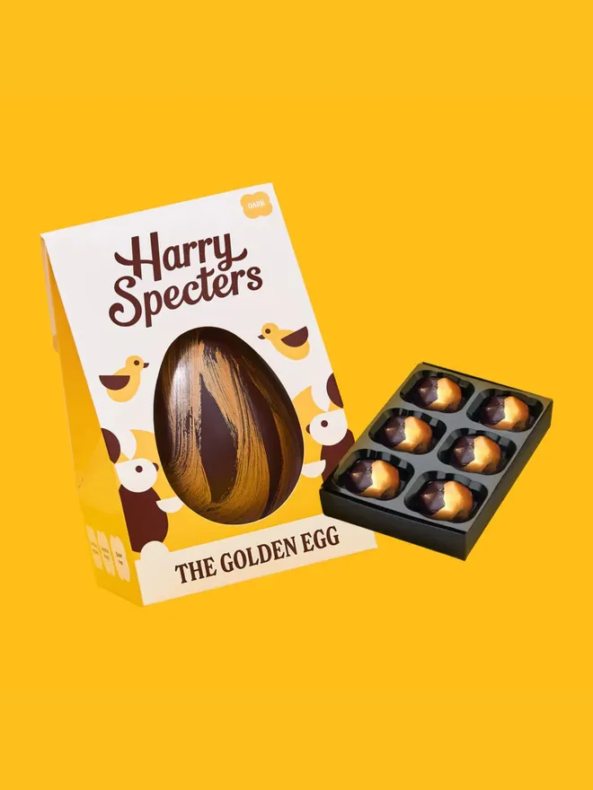 A dark chocolate Easter egg decorated with gold cocoa butter, next to a small box of luxury dark chocolates