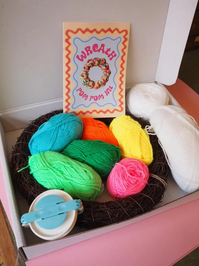 Inside the Floral Wreath Kit is a range of bright coloured yarns, a pom pom maker, a wreath base and instructions