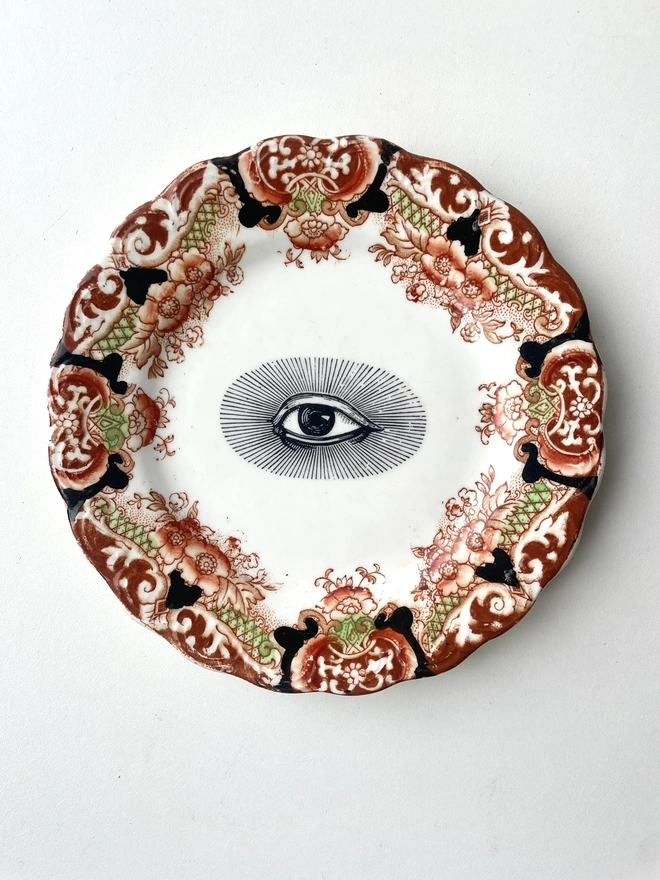 an ornate vintage plate with detailed border and in the centre an vintage illustration of an eye
