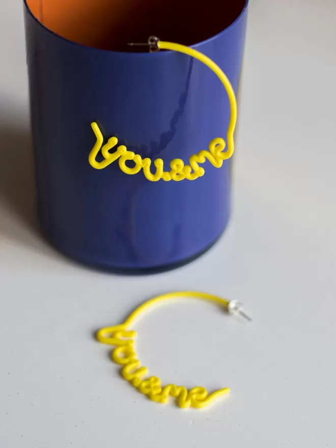 You & Me hoops by Zoe Sherwood seen in yellow in a blue cup.