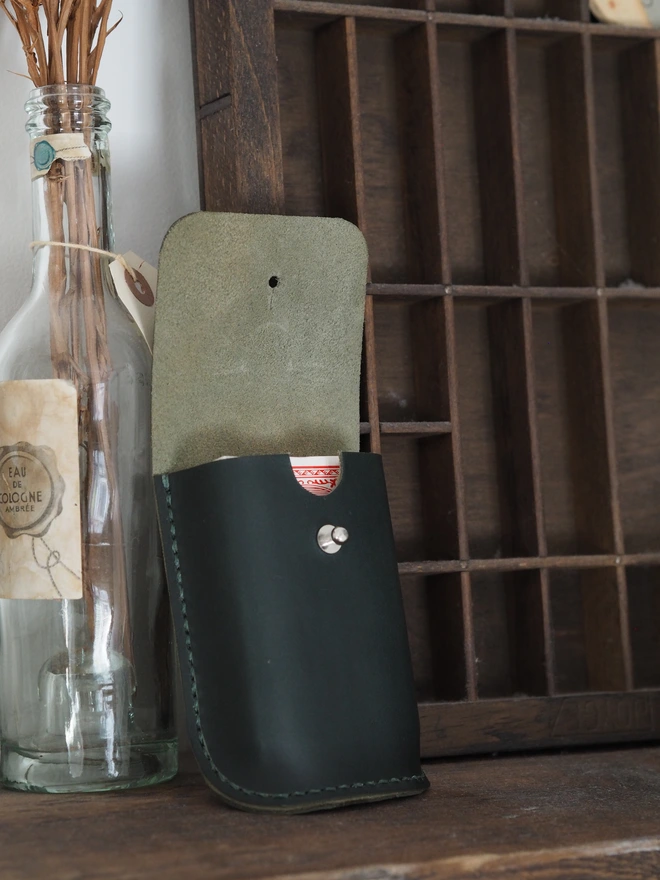 Handmade leather playing card holder. A deck of cards and a bottle green leather case designed to hold them.