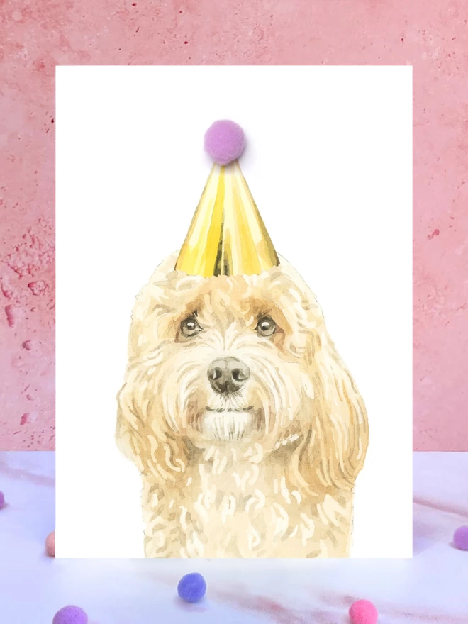 Apricot Cavapoo Pompom Birthday Card in front of a pink background and surrounded by pompoms