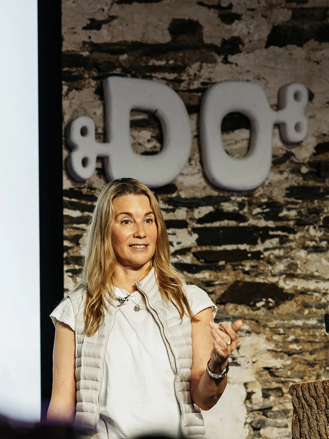 Woman with blonde hair standing on stage mid-talk