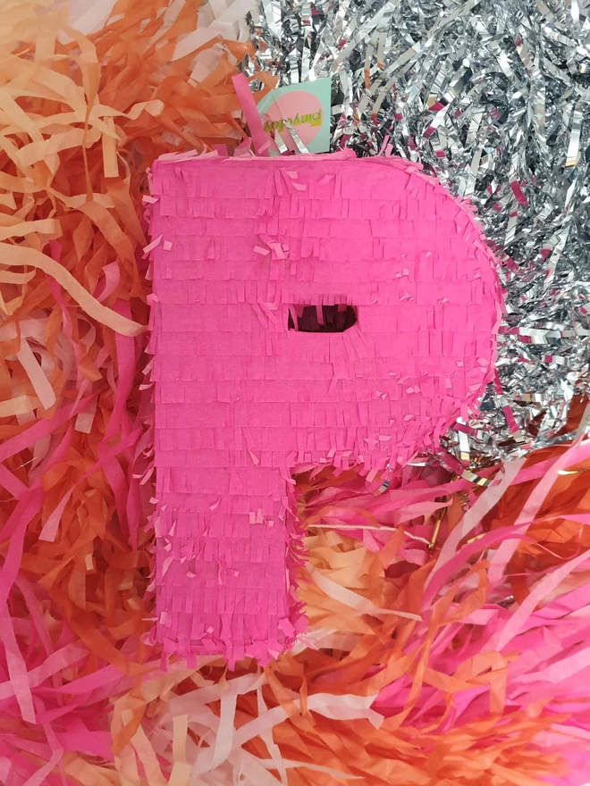 Bright Pink letter P Pinata on a background of paper streamers