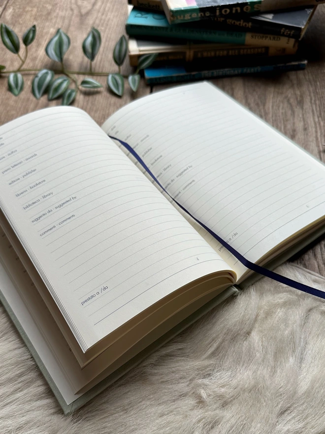 A reading journal lies open on a table and you can see how the journal needs to be filled in.