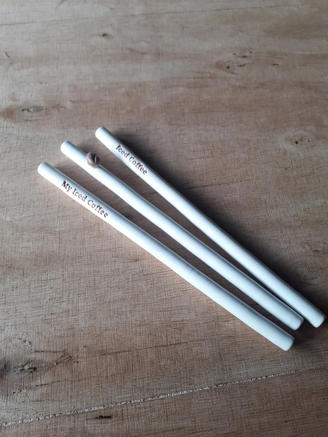Set of reusable ceramic iced coffee straws, handmade in Wales with coffee bean and lettering motifs, sustainable alternative to plastic straws
